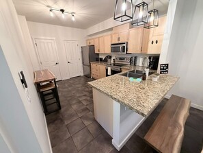 A modern kitchen with granite countertops, stainless steel appliances, and wooden cabinets. - ⛰️ Spacious Mountain Condo | Sleeps 8 guests (Canmore)