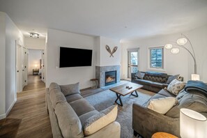 Ein modernes Wohnzimmer mit Kamin, Fernseher und einer Sofagarnitur.