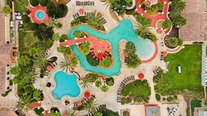 A resort with multiple swimming pools, sun loungers, and palm trees. - NO HIDDEN FEES! Escape to this comfy 4-bed, 3-bath townhome in gated resort! Relax at the tropical pool with lazy river & waterslide, plus Spa, arcade, gym, business center & dining. Ideal family spot just minutes from all Orlando attractions. (Davenport)