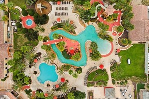 A resort with multiple swimming pools, sun loungers, and palm trees. - NO HIDDEN FEES! Escape to this comfy 4-bed, 3-bath townhome in gated resort! Relax at the tropical pool with lazy river & waterslide, plus Spa, arcade, gym, business center & dining. Ideal family spot just minutes from all Orlando attractions. (Davenport)