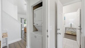 A laundry area with a washing machine and a drying rack. - NO HIDDEN FEES! Escape to this comfy 4-bed, 3-bath townhome in gated resort! Relax at the tropical pool with lazy river & waterslide, plus Spa, arcade, gym, business center & dining. Ideal family spot just minutes from all Orlando attractions. (Davenport)