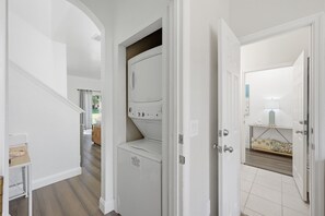 A laundry area with a washing machine and a drying rack. - NO HIDDEN FEES! Escape to this comfy 4-bed, 3-bath townhome in gated resort! Relax at the tropical pool with lazy river & waterslide, plus Spa, arcade, gym, business center & dining. Ideal family spot just minutes from all Orlando attractions. (Davenport)
