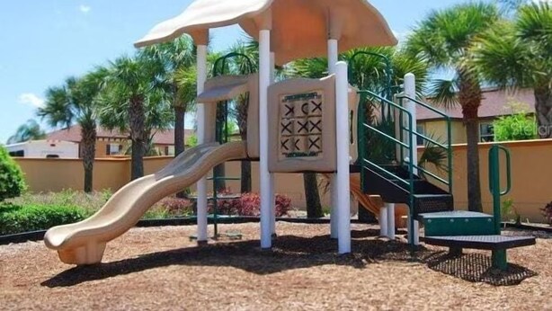 A playground with a slide and climbing structure, surrounded by palm trees and a clear sky. - NO HIDDEN FEES! Escape to this comfy 4-bed, 3-bath townhome in gated resort! Relax at the tropical pool with lazy river & waterslide, plus Spa, arcade, gym, business center & dining. Ideal family spot just minutes from all Orlando attractions. (Davenport)
