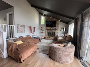 Uma sala de estar com sofá, um espaço de estar circular, lareira e televisão.