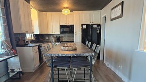 A modern kitchen with a dining area, featuring a large island, built-in appliances, and a rustic ceiling. - Barefoot Boho Bay - Morse - Cicero Indiana (Cicero)