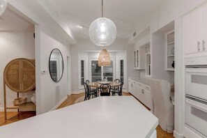 A modern kitchen with white cabinetry, a large island, and a hanging pendant light. - Waterfront Bunk Retreat w/ Pool, Jamaica Beach (Jamaica Beach)