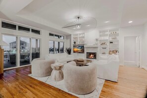 A modern living room with a fireplace, white furniture, and a large window overlooking a cityscape.