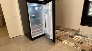 A kitchen with a refrigerator, a patterned backsplash, and a tiled floor. - IN THE HEART OF CATANIA — THE PETITE SUITE SAN GIULIANO (Catania)