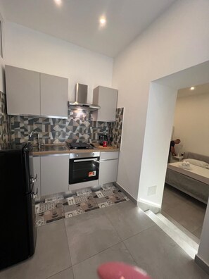 A compact kitchen with modern appliances, a patterned backsplash, and a small oven. - IN THE HEART OF CATANIA — THE PETITE SUITE SAN GIULIANO (Catania)