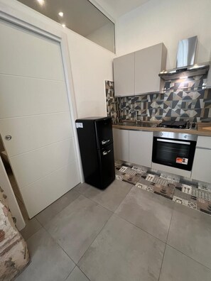 Eine kleine Küche mit Kühlschrank, Herd und Backofen.