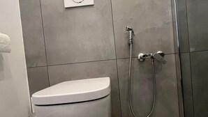 A modern bathroom with a toilet, a shower, and a wall-mounted control panel. - IN THE HEART OF CATANIA — THE PETITE SUITE SAN GIULIANO (Catania)