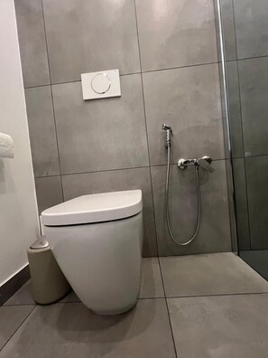 Ein modernes Badezimmer mit Toilette, Dusche und einer Wandbedienung.