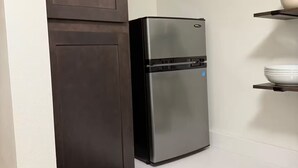 Eine Küche mit einem Edelstahl-Kühlschrank, dunklen Holzschränken und einer weißen Arbeitsplatte.