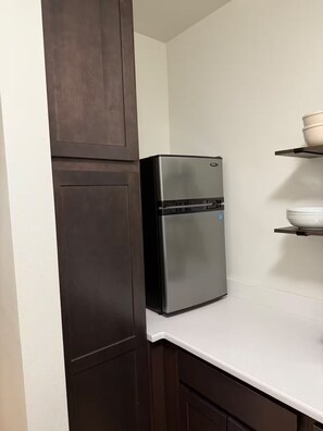 Eine Küche mit einem Edelstahl-Kühlschrank, dunklen Holzschränken und einer weißen Arbeitsplatte.