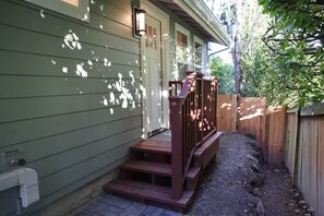 Um deck de madeira com uma escadaria que leva a uma casa com fachada verde.
