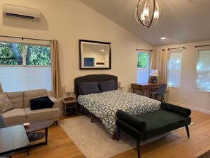 Quarto de hotel moderno com uma cama grande, um sofá, uma escrivaninha e uma cadeira.