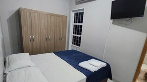 Une chambre comprenant un lit, une armoire, une fenêtre, un appareil de climatisation et un téléviseur.