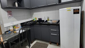 Une cuisine avec des meubles de couleur sombre, un réfrigérateur blanc, un four à micro-ondes et une cuisinière.