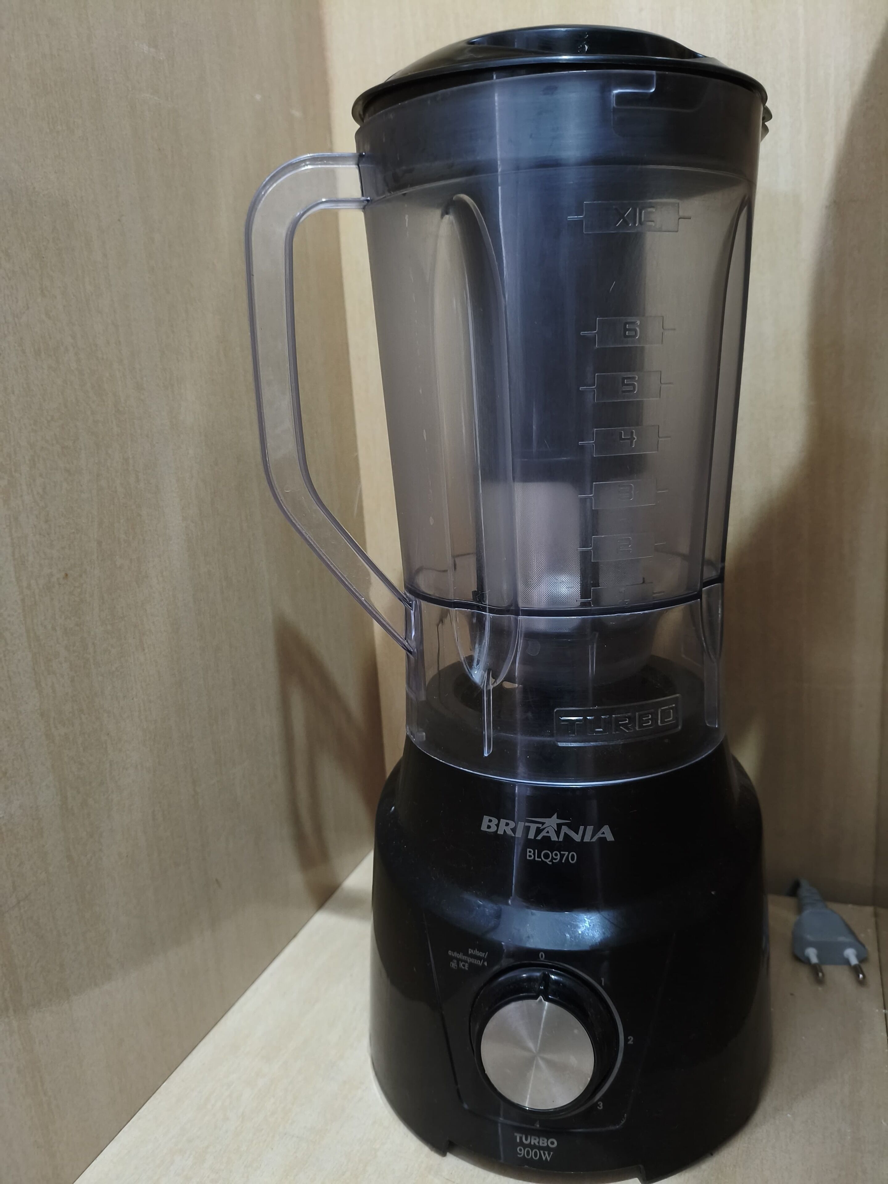 A black Britanna BLQ970 Turbo 900W blender with a clear container and a handle, placed on a wooden surface.