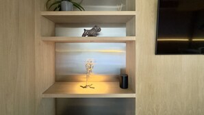 Una estantería de madera con adornos, una planta en maceta y una figurita.