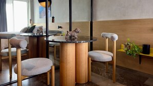 Un comedor moderno con mesas redondas, sillas acolchadas y una estatua decorativa de un perro.