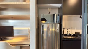 Una cocina moderna con refrigerador incorporado, un comedor con una silla blanca y un televisor.