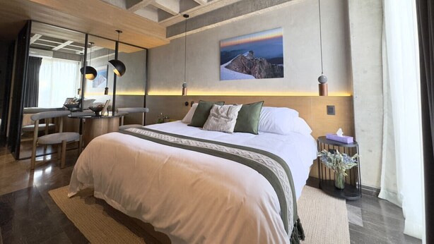 Habitación de hotel moderna con una cama grande, un escritorio y vistas a la montaña.