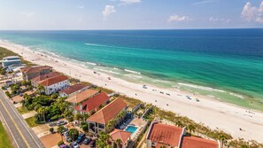 A coastal hotel with a beach view, a swimming pool, and a road leading to the beach. - Shore Beats Work - Gulf Views, Pool, Elevator, Beach Access (Panama City Beach)
