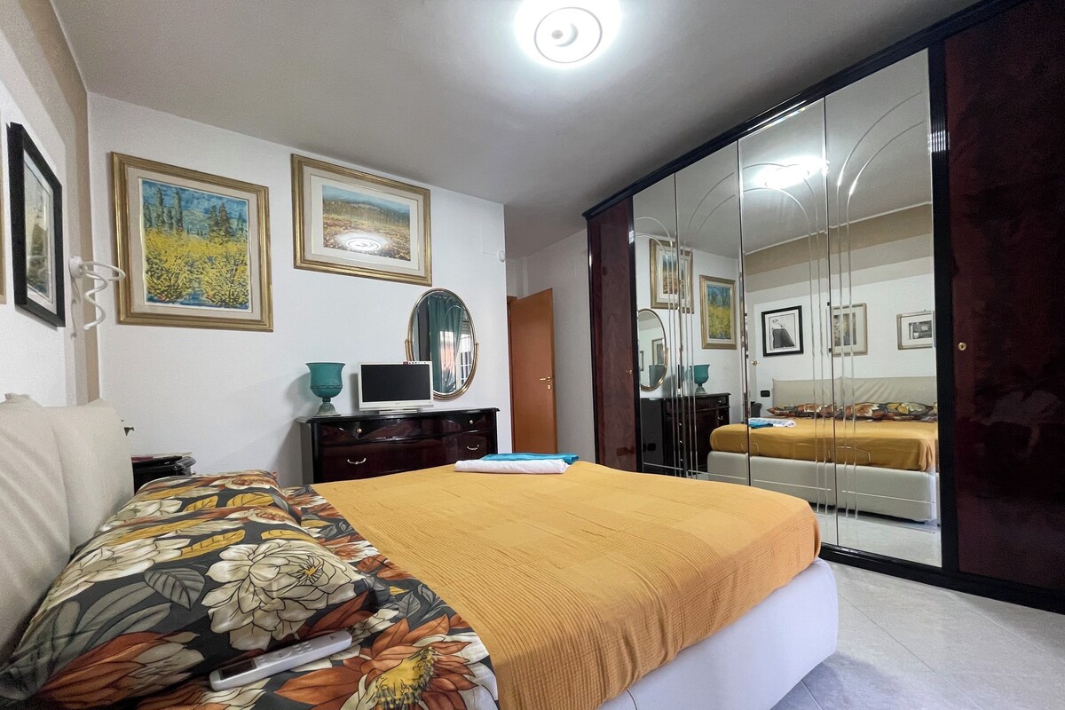 A bedroom with a bed, a dresser, a television, and a mirror.