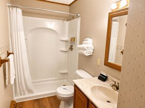 Ein Badezimmer mit Dusche, Toilette, Waschbecken und Spiegel.