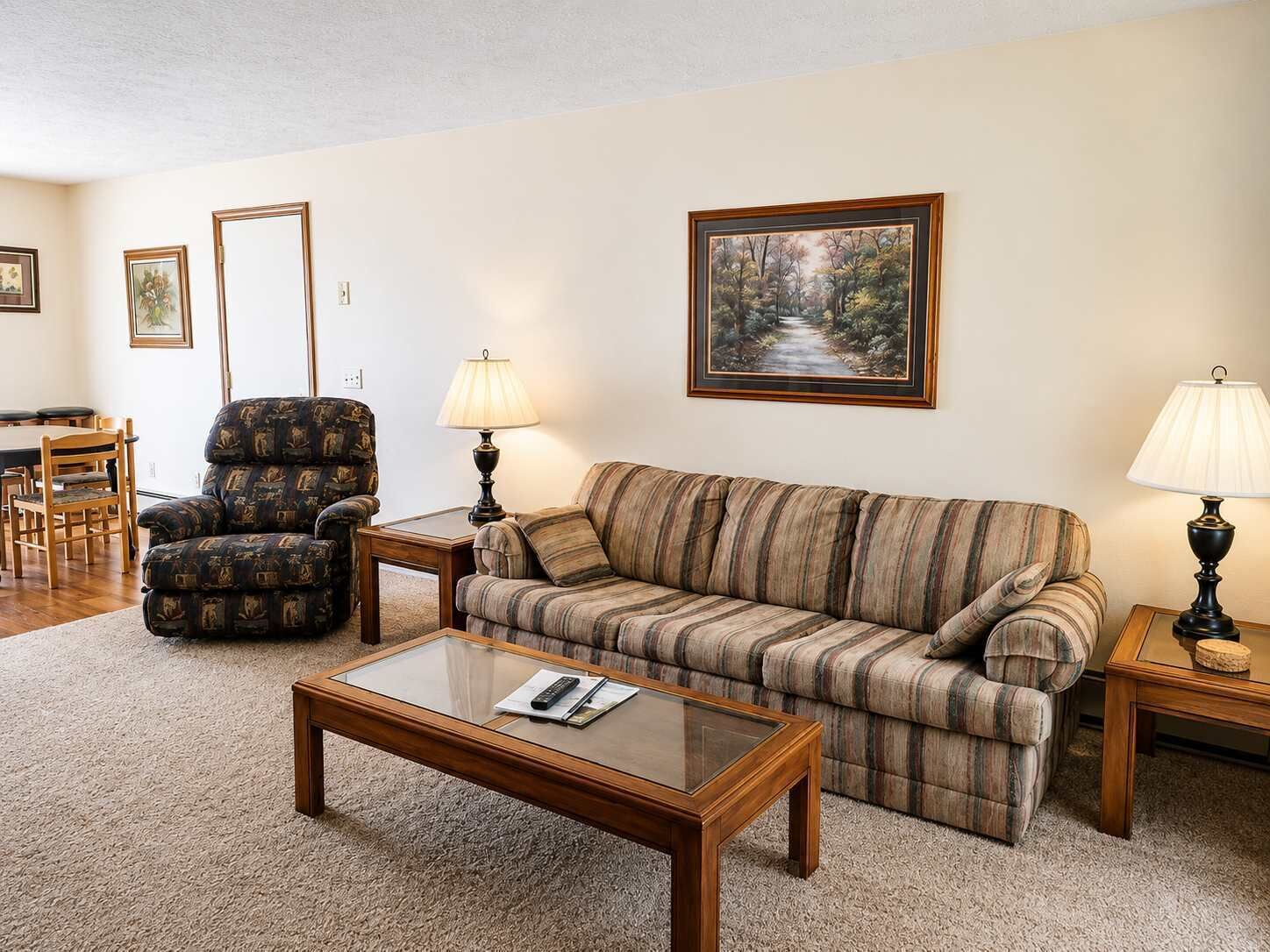Una sala de estar con sofá, sillón, mesa de centro y lámparas.