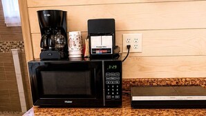 Eine kleine Küche mit Mikrowelle, Kaffeemaschine und einem kleinen Kühlschrank.