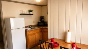 Eine kleine Küche mit Kühlschrank, Mikrowelle und Holzschränken.