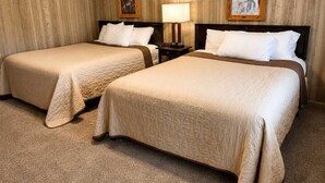 Een hotelkamer met twee bedden, houten paneelwanden en twee ingelijste foto's.