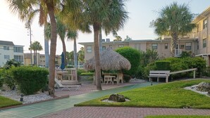 A courtyard with a thatched-roof gazebo, lounge chairs, and a shuffleboard court. - The Tropical Garden Paradise🌴 on St. Pete Beach🌞⛱️🌊Friendly Native #802 (St. Pete Beach)