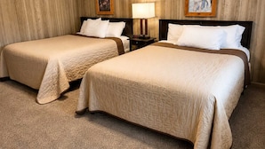 A hotel room with two beds, wooden panel walls, and two framed pictures. - Pet Friendly Room 23-2 Queen Suite-Woodland Motor Lodge (Grayling)