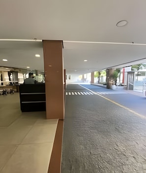 Um hall amplo com balcão de recepção, passadeira para o exterior e um design arquitetônico moderno.