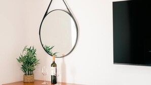 Ein Holzkonsolentisch mit einem runden Spiegel, einer Weinflasche und einem Glas.