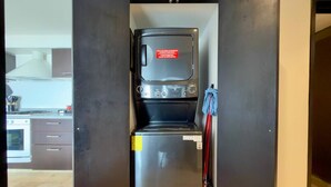 Eine kompakte Küche mit eingebauter Waschmaschine und Trockner, einem Kühlschrank und einer Mikrowelle.
