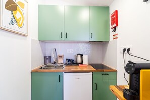 A compact kitchen with green cabinets, a white refrigerator, a sink, and a coffee machine. - GuestReady-Charming Studio in Funchal's Heart (Funchal)