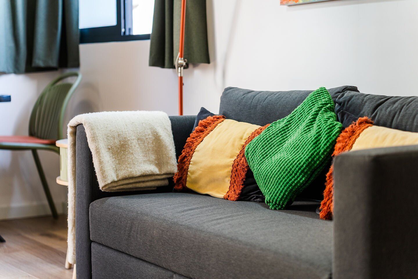 Un sofá gris con una manta blanca y almohadones coloridos.