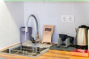 A kitchen with a built-in sink, a kettle, a coffee maker, and a cleaning kit on the counter. - GuestReady-Charming Studio in Funchal's Heart (Funchal)