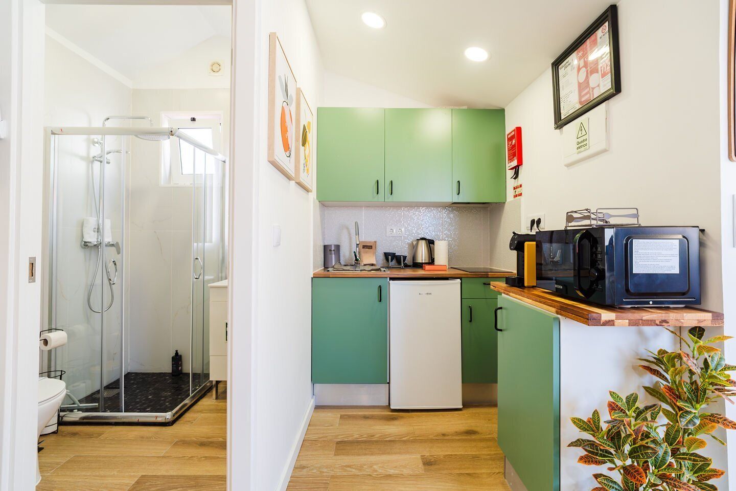 Una cocina compacta equipada con microondas, un refrigerador pequeño y un lavamanos.