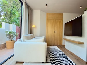 Ein modernes Wohnzimmer mit einer Couch, einem Fernseher, einem Holzschrank und einem Topfpflanzen.