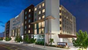 Ett hotell med flera våningar och modern design, med en framträdande entré och en skylt som visar att det är ett Staybridge-hotell.
