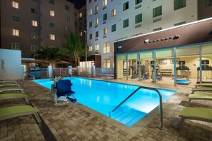 A swimming pool with lounge chairs, a gym, and a building with a sign that reads "Hotel". - ADA Queen Studio w/ Tub | Free Breakfast! (Miami)