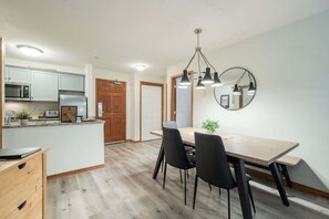 Eine moderne Küche mit Essbereich, Holzschränken und einem großen Spiegel.