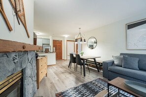 Ein modernes Wohnzimmer mit Kamin, Essbereich und einer Küche im Hintergrund.