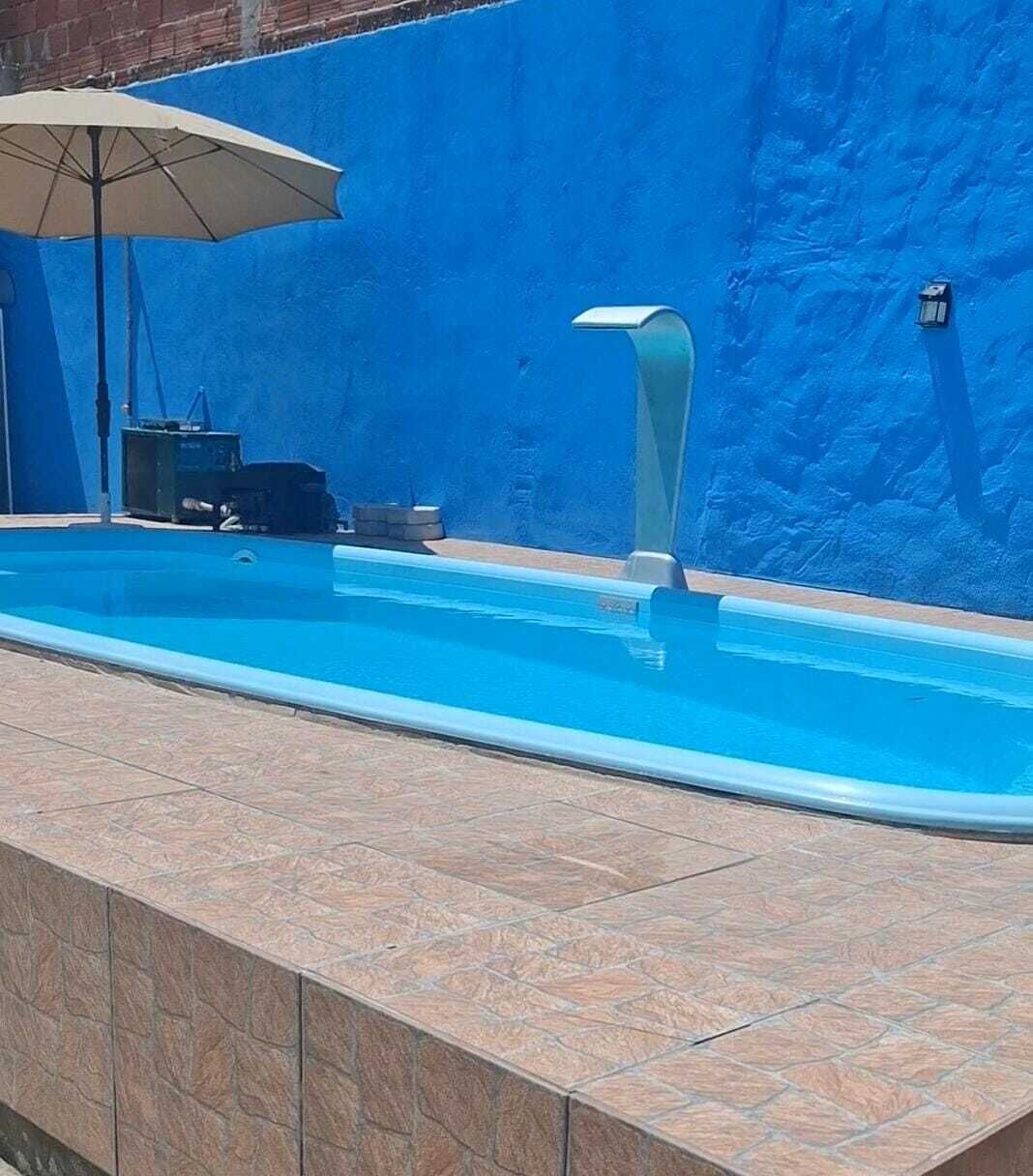 A swimming pool with a blue tiled edge, a poolside umbrella, and a wall with a textured pattern.