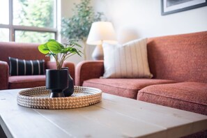 Ett vardagsrum med en soffa, ett soffbord med en växt och en lampa.